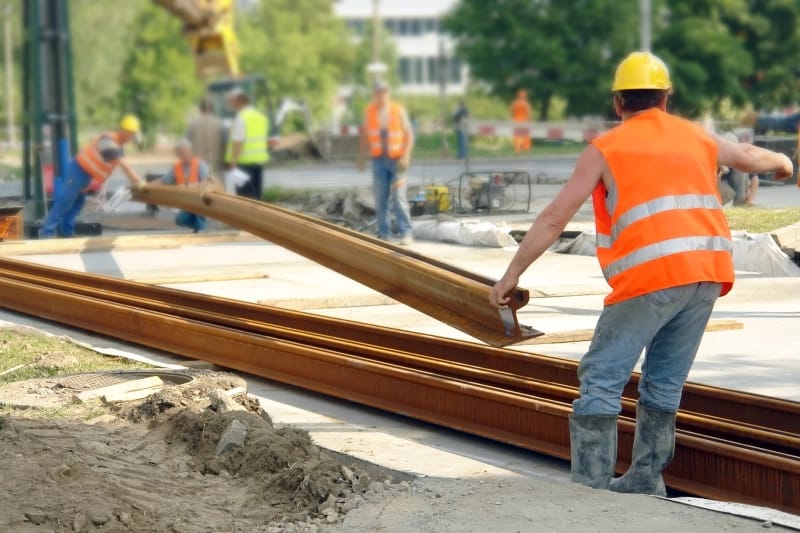 Budowa torowiska tramwajowego. Pracownicy budują nową linię torów na jezdni.